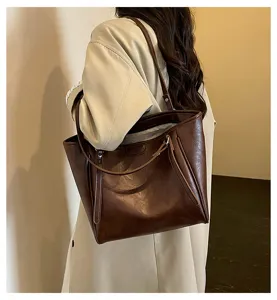Detailopname van een bruine PU lederen grote schoudertas shopper tas voor dames dagelijks.