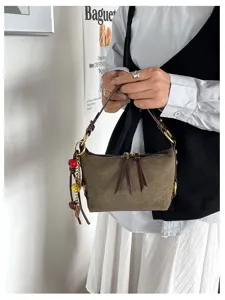 Close-up detail van vintage bruine suade kussen handtas met rits en bedels.