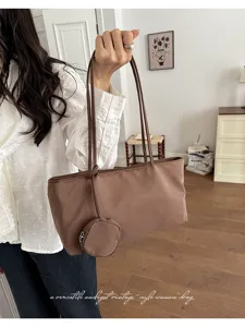 Detail shot of the brown nylon underarm shoulder bag with coin purse in lifestyle scene.