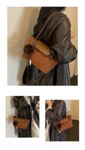 Detailansicht einer braunen Vintage Wildleder Umhängetasche mit niedlichem Bommel für Damen.