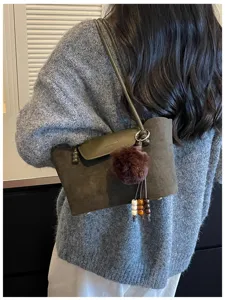 Detailansicht der lässigen Wildleder Umhängetasche mit stilvollem Bommel und Retro Look.