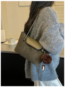 Lässige Retro Damen Umhängetasche mit pelzigem Pompom Anhänger und elegantem Überschlag-Design.
