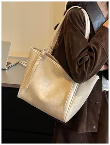 Close-up van een minimalisten beige lederen schoudertas gedragen door model, moderne stijl.