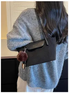 Schwarze Umhängetasche mit flauschigem Bommel und Perlenriemen für stilvollen Alltagslook.