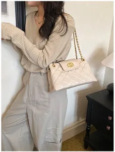 Detailed shot of women beige quilted chain shoulder bag, elegant commuting underarm handbag style.