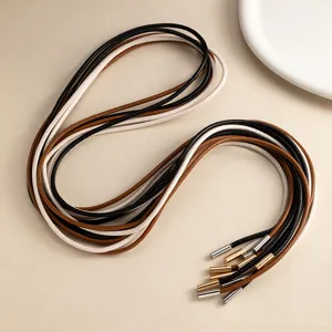 Vista detallada de finos cordones de cuero multicolor con elegantes puntas metálicas decorativas.