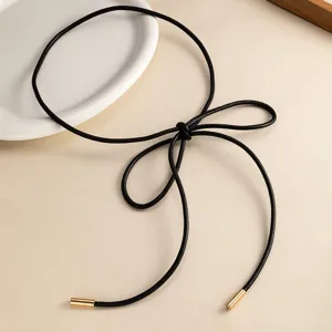 Primer plano detallado de un elegante cinturón de cordón de cuero negro con puntas doradas.
