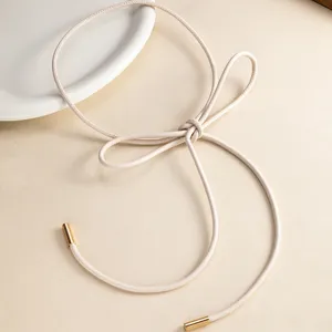 Primer plano detalle de un cinturón fino de piel beige minimalista con elegante lazo.
