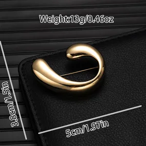 Detailed close-up view of golden abstract swirl brooch with polished metallic texture.