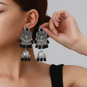 Gros plan détaillé de boucles d'oreilles ethniques argentées avec franges et perles noires.
