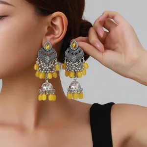 Gros plan détaillé de boucles d'oreilles pendantes argentées ethniques vintage avec des pierres.