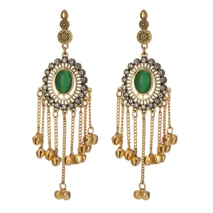 Detailed shot of Indian vintage gold long tassel bell earrings with green stone and rhinestones.