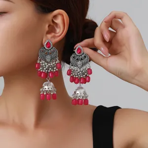 Vue rapprochée détaillée de boucles d'oreilles ethniques vintage avec perles roses.