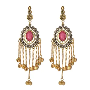 Close-up detail of Indian style long tassel bell earrings with pink center stone and rhinestones.