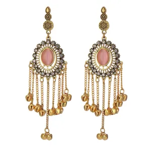 Detailed closeup of Indian style gold tassel bell earrings with pink stones and rhinestones.