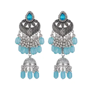 Gros plan de boucles d'oreilles pendantes argentées ethniques vintage avec perles bleues.