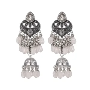Gros plan detail des boucles doreilles ethniques en argent avec pampilles blanches.