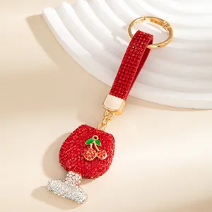 Vista dettagliata del portachiavi a forma di bicchiere di vino in strass rossi con ciliegia.