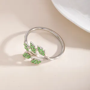 Portatovaglioli in metallo con design a foglia e strass verdi per elegante tavola.