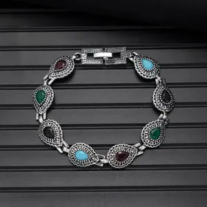 Vintage silver tone bracelet detail showcasing multi-color teardrop stone charms.