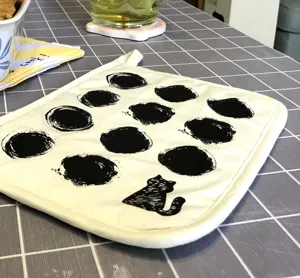 Detailed close-up shot of the cotton pot holder featuring unique black cat and abstract dots.
