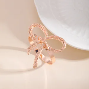 Primo piano di elegante portatovagliolo a fiocco oro rosa, finitura metallica per tavola.
