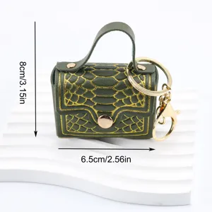 Gros plan détail du mini sac à main porte-clés vert avec motif serpent doré et belle finition.