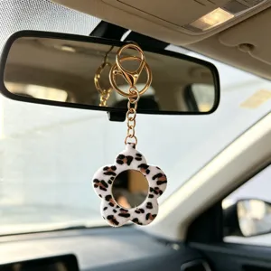 Charmant porte-clés miroir en peluche motif léopard fleur détail suspendu sur rétroviseur de voiture.