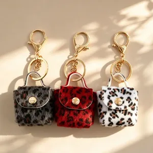 Detailopname van zachte pluche luipaardprint mini tas sleutelhangers met gouden metalen hardware.