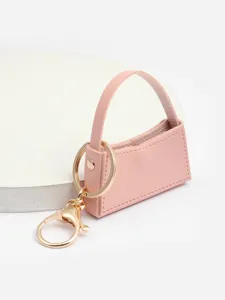 Vue rapprochée d'un mini porte-clés sac à main en cuir PU rose avec des anneaux dorés.