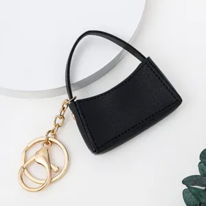 Gros plan d'un mini porte-clés sac à main en cuir PU noir avec des détails métalliques.