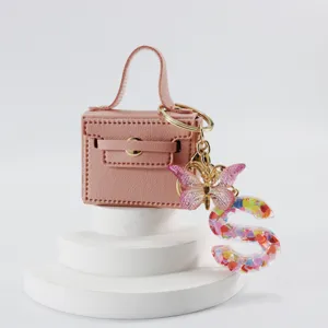 Portachiavi borsa mini in pelle rosa con farfalla e ciondolo lettera S in resina.
