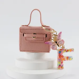 Portachiavi borsa mini in pelle rosa con ciondolo farfalla e lettera F vista principale.