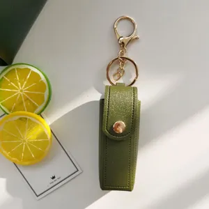 Portachiavi con custodia per rossetto in pelle verde con parti dorate per borsa.
