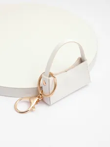 Vue détaillée du porte-clés mini sac à main en cuir PU blanc avec accessoires dorés
