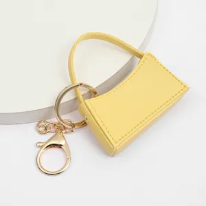 Gros plan détail du porte-clés sac à main miniature en cuir PU jaune avec anneau.
