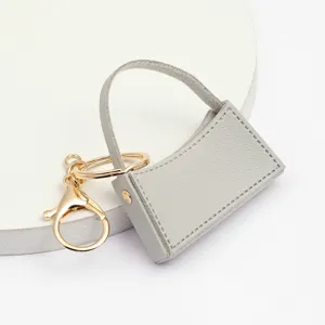 Porte-clés mini sac à main en cuir PU gris avec élégants accessoires métalliques.