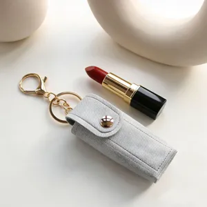 Mini portarossetto in pelle con texture denim e anello portachiavi dorato elegante.