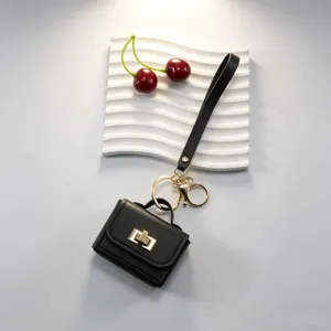 Mini sac à main en cuir noir porte-clés et étui à écouteurs avec serrure dorée élégante.