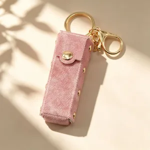 Roze denim stof lipstick etui sleutelhanger met retro klinknagels en gouden hardware.
