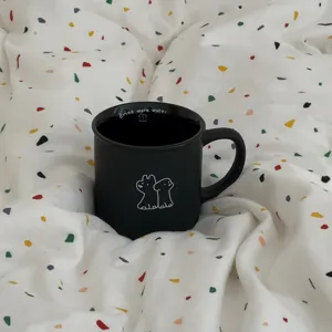 Matte black ceramic coffee mug featuring cute puppy illustration and inner text detail.