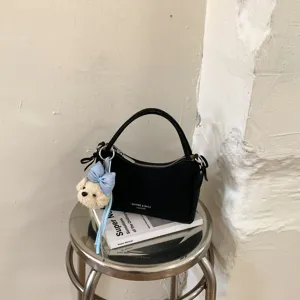 Fashion black leather women handbag with cute bear pendant, stylish crossbody shoulder bag.