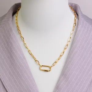 Close-up detail of a fashionable gold paperclip chain necklace with a carabiner lock pendant.