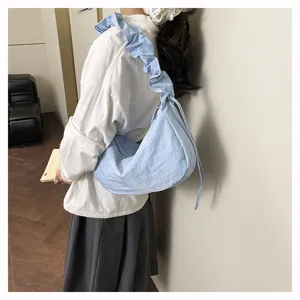 Detailed view of casual light blue ruffled shoulder crossbody dumpling bag worn by model.