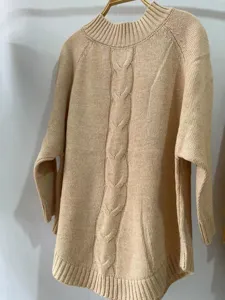 Detailed close-up shot of the elegant beige cable knit sweater featuring a comfortable high neckline.