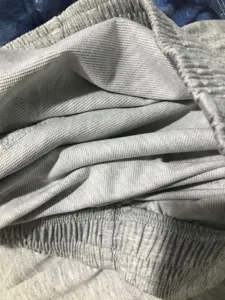 Grauer Fleece-Jogginghose Stoffdetail, weiches dickes Material und elastischer Bund.