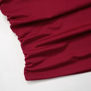 Dettaglio in primo piano del tessuto arricciato rosso vino con eleganti elementi.