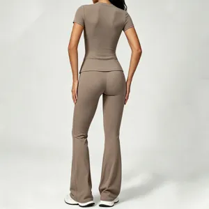 Back view of women's short sleeve fitness top and flare yoga pants set in beige color.