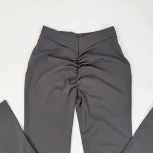 Close-up detail of dark grey high V-waist yoga flare pants with scrunch back peach lift design.