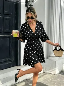 Detailed view of the stylish black and white polka dot summer mini dress with V-neck design.